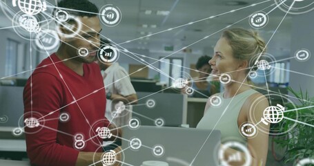 Collaborating coworkers reviewing network icons on laptop in open-plan workspace, with coffee cups