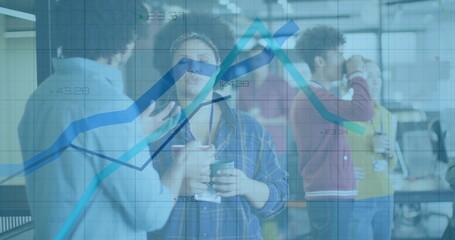 Chatting coworkers holding coffee mugs and checking laptop at office break area, with data chart