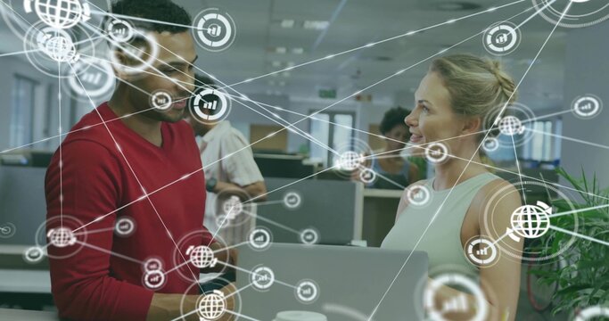 Collaborating coworkers reviewing network icons on laptop in open-plan workspace, with coffee cups - Powered by Adobe