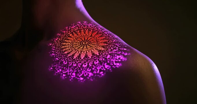 Mandala projection pulsing across model's back shimmering with water droplets in dark studio - Powered by Adobe