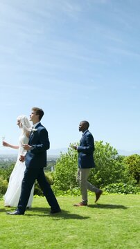 Vertical video: Diverse wedding party entering lawn sipping champagne inviting guest to toast