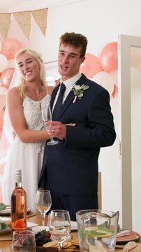 Vertical video: As groom lifting flute toasting guests, newlywed couple clinking glasses at venue
