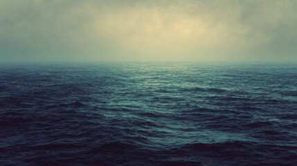 Fototapeta premium A serene ocean view with gentle waves under a misty, atmospheric sky.