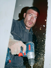 Male construction worker holds a rotary hammer in his hand at a construction site. Engineering and construction tasks.