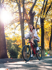 Fototapeta premium A young woman enjoys a pleasant bike ride in an autumn park. Active recreation in the city