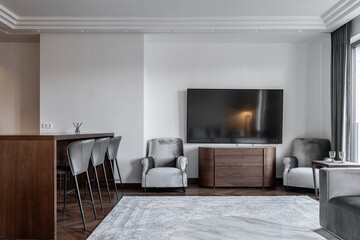 large modern living room combined with kitchen. Grey sofa, parquet flooring, wooden kitchen furniture, kitchen table and chairs.