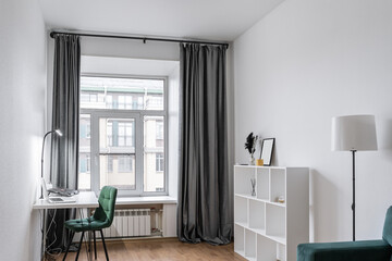 The interior of a simple living room with light walls, a green sofa, and a floor lamp. the atmosphere is cozy and relaxed.