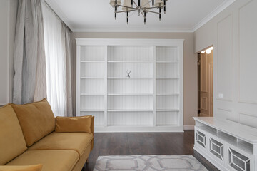 design of stylish living room with stylish yellow sofas, floor lamp next to sofa, beautiful large chandelier on ceiling, and soft carpet on floor. White cabinets and shelves. Architecture inside home