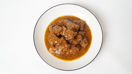 Beef stew is beef stewed with soy sauce and spices, served on a white plate with a white base and background.