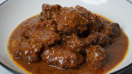 Beef stew is beef stewed with soy sauce and spices, served on a white plate with a white base and background.