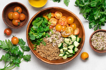 Gluten Free Quinoa Salad with Cucumber, Parsley, Mint and Yellow Cherry Tomatoes in Wooden Bowl on Light Background