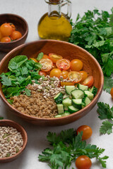 Gluten Free Quinoa Salad with Cucumber, Parsley, Mint and Yellow Cherry Tomatoes in Wooden Bowl on Light Background