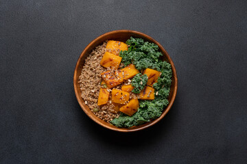 Healthy Autumn Harvest Bowl with Quinoa, Green Buckwheat, Roasted Pumpkin, and Kale in Wooden Bowl on Black Background