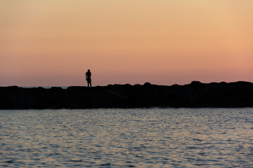 Silhouette of a Man Standing on a Pier at Sunset