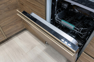 Open dishwasher with wood panel door, showing racks inside. Sleek, modern kitchen appliance