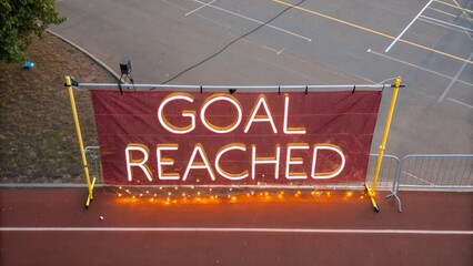 Bright Neon Goal Reached Sign Displayed at Outdoor Event Site