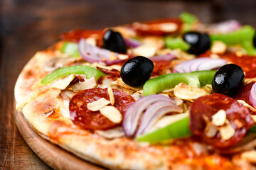 Pizza with chorizo ​​sausage, mozzarella cheese, green pepper and black olives. Rustic wooden background. Soft focus.	