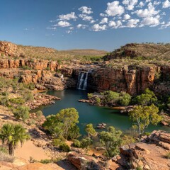 A breathtaking vista of a cascading waterfall plunging into a tranquil pool surrounded by vibrant outback scenery.