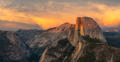 Fototapeta premium This scenic sunset panorama features a vibrantly colored sky over Half Dome and Clouds Rest, located in Yosemite National Park, California.