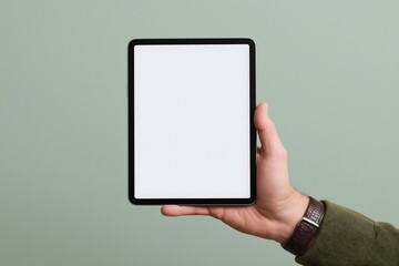 Hand holding tablet  mockup with a blank screen against muted green background