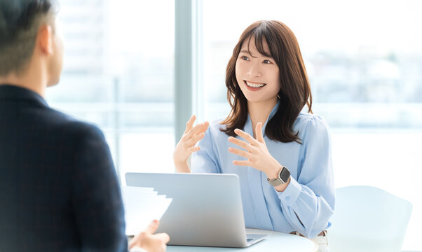 ノートパソコンを前に打ち合わせをするビジネスウーマンのミーティング風景, Businesswoman discussing ideas with a laptop in a meeting scene