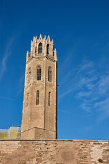 Obraz premium Vertical view of the Gothic tower of the Old Cathedral of Lleida in Catalonia illuminated by the sun against a clear sky