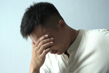 Fototapeta premium An asian businessman is suffering from headache, tension from forehead and getting stress and depression during working, massaging his head, employee life office stress and office syndrome concept. 