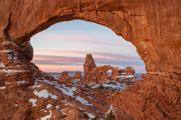 This scenic winter photograph of Arches National Park features colorful clouds above Turret Arch, captured through North Window. © Nick Monitello