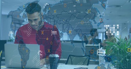 Typing Hispanic man at office desk, with laptop under world map overlay with icons
