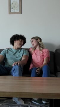 Vertical video: Couple reacting to noise unfolding fabric from box on coffee table examining it