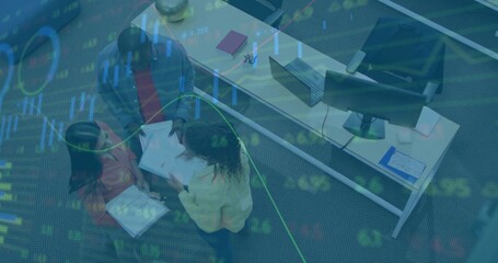 Reviewing team examining printed documents beside laptop and monitors in modern office, copy space