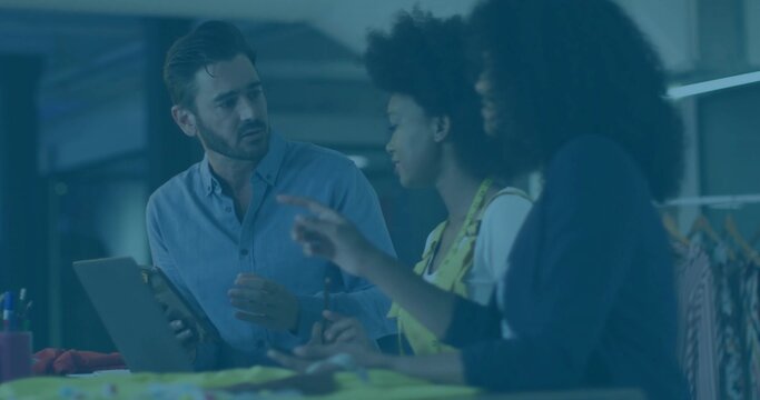 Collaborating designers examining swatches on table in design studio, with tablet and tape measure