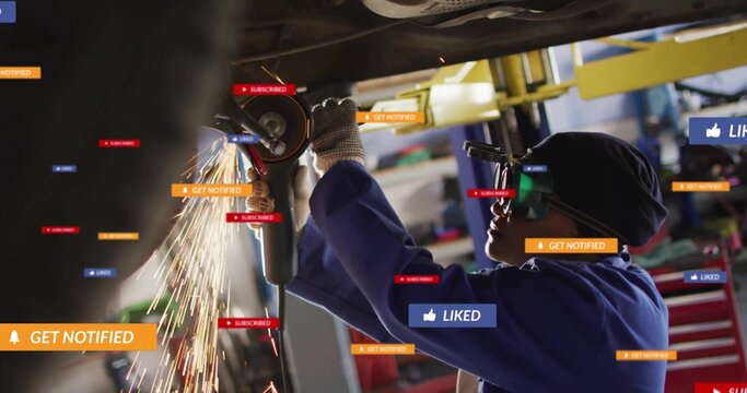 Mechanic wearing gloves grinding under chassis in workshop, with angle grinder sparks, copy space