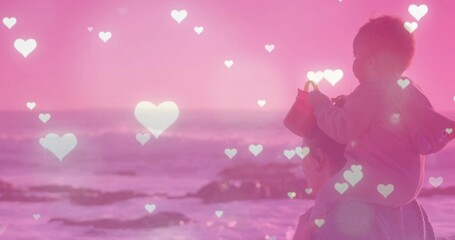 Standing mother and baby boy gazing at shoreline, with red bucket and heart overlays, copy space