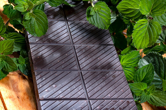 tableta de chocolatada con menta fresca sobre una madera de color claro