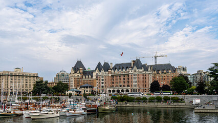 Victoria inner harbour causeway glows warmly at sunset with shimmering water reflecting the colourful sky, boats gently bobbing, and the city's historic skyline creating a serene, picturesque scene.