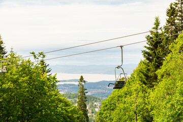 Chairlift ascending over lush green forest in Oslo, Norway