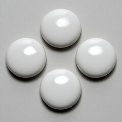 Four round, glossy, white buttons arranged in a diamond pattern on a neutral background