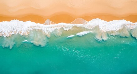 Fototapeta premium An aerial view of waves crashing on a sandy beach, creating a beautiful contrast between the turquoise water and the golden sand