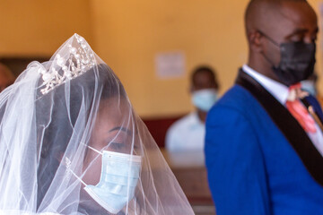 African Bride in Focus with Groom Beside, Both Wearing Disposable Face Masks