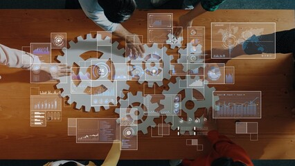 Dynamic business meeting showcasing teamwork and data analysis with gears and digital graphics on a wooden table for innovative strategy development. Raster
