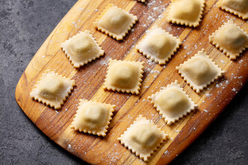 Ravioli on a wooden board. Grey background. Close up.