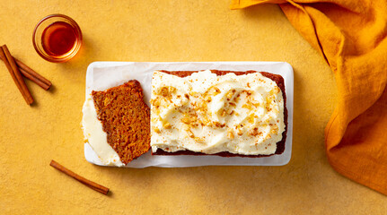 Carrot cake loaf on a white marble board. Yellow background. Top view.