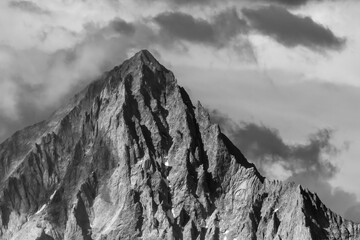 Snowy rock illuminated by sun with twilight in steep mountains