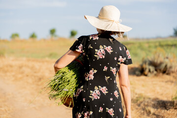 Farmer walking away carrying freshly harvested wheat in basket on sunny day