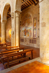 Obraz premium Interior of Church of Santa Maria Assunta showcasing frescoes and wooden pews in Monteriggioni, Italy