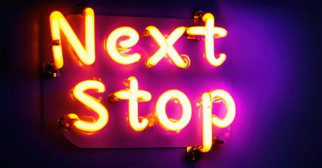 Bright neon sign displays words Next Stop. Vivid yellow glows against purple backdrop. Simple design, dark background creates contrast.
