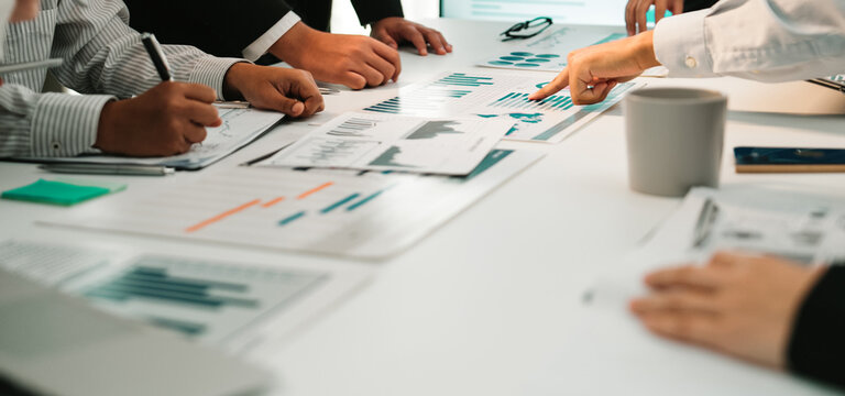 Team members engaged in a collaborative meeting focusing on data trends, utilizing charts and reports to strategize and plan actions for future business growth. SACTR