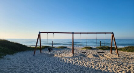 Empty swings on a beach at sunrise. Calm ocean vista