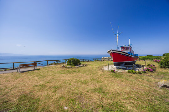Fototapeta Red fishing boat overlooking the Cantabrian Sea in Cudillero, Asturias, Spain